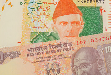 A macro image of a orange ten rupee bill from India paired up with a orange and green 20 rupee note from Pakistan.  Shot close up in macro.