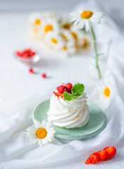 A close image of the dessert by anna pavlova decorated with strawberries and mint leaves