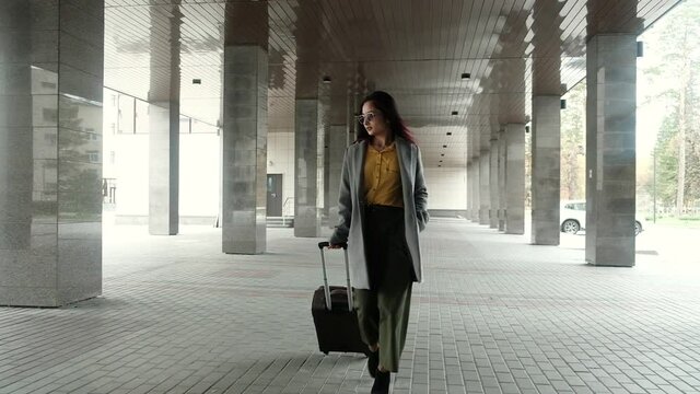 business woman successful stylish young Asian woman goes from train station or airport to taxi with a suitcase Luggage in Parking lot. woman returned from vacation to the city.