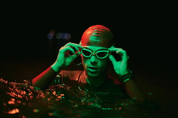 authentic triathlete swimmer having a break during hard training on night neon gel light