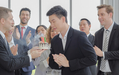 Senior manager and team staff celebrating birthday surprised, clapping hands to young asian business man after meeting in the office. Selective focus.
