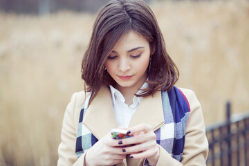 Closeup portrait serious woman talking texting on phone displeased with conversation isolated on light brown park nature background. Negative human emotion face expression feeling