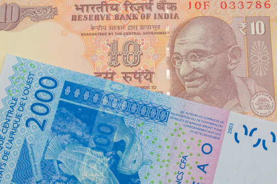 A macro image of a orange ten rupee bill from India paired up with a blue, two thousand West African franc bank note.  Shot close up in macro.