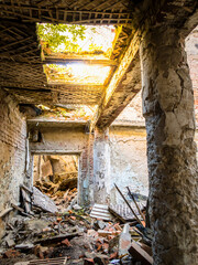 Corridor with construction debris, shabby walls, peeling columns and holes in the ceiling