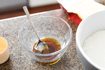 Golden syrup glass mixing bowl with spoon ready for ingredients in a domestic kitchen setting.