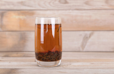A cup of brewed black tea on wooden background