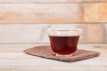 A bowl of freshly brewed black tea on a wooden background