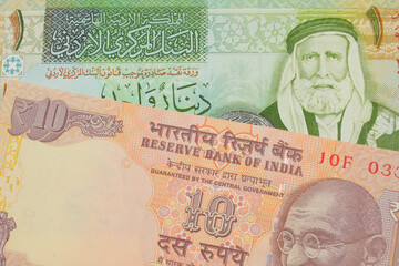 A macro image of a orange ten rupee bill from India paired up with a green and yellow one dinar note from Jordan.  Shot close up in macro.