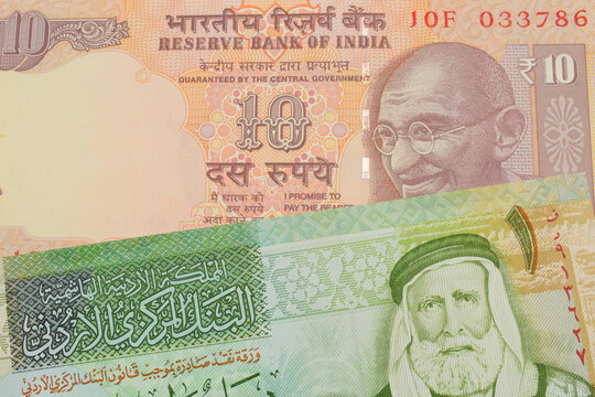 A macro image of a orange ten rupee bill from India paired up with a green and yellow one dinar note from Jordan.  Shot close up in macro.