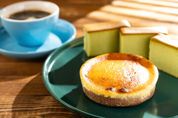 cheese cake with matcha cakes and cup of coffee at background in a sunny morning horizontal composition