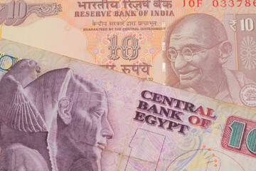 A macro image of a orange ten rupee bill from India paired up with a pink and purple ten pound bank note from Egypt.  Shot close up in macro.