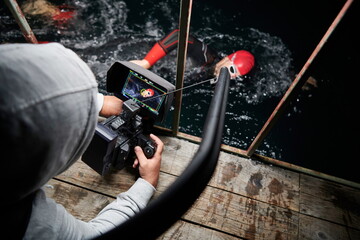 videographer taking action shot of triathlon swimming athlete at night