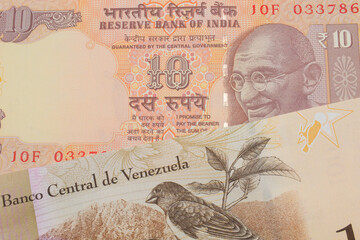 A macro image of a orange ten rupee bill from India paired up with a colorful one hundred Bolivar bank note from Venezuela.  Shot close up in macro.