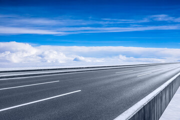 Fototapeta premium Empty asphalt road and blue sky with white clouds scenery.