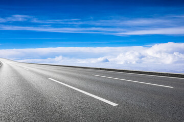 Empty asphalt road and blue sky with white clouds scenery.