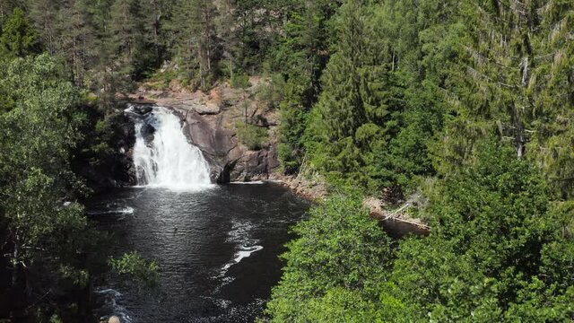 Kaja Waterfall or Kajafoss in Green Forest of Norway, Aerial Descent