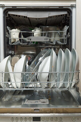 Dirty dish in open integrated dishwasher. Open dishwasher with dirty dishes inside before washing. full loaded dishwasher ready for washing.