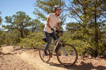 Cyclist man rides a mountain bike through a forest path in Santa Fe, New Mexico while mountain biking down the mountain