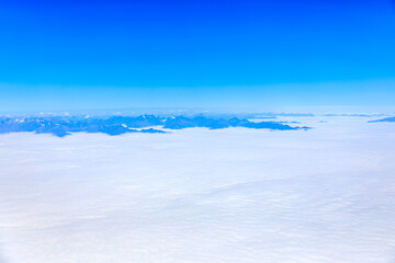 Aerial view above the clouds and mountain peaks on a sunny day.mountain view from airplane.
