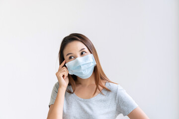 Portrait of happy charming young Asian girl with protective face mask and t shirt looks to the side, thinking and plan something. Isolated over white background. Copy space