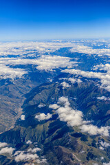 Aerial view above the clouds and mountain peaks on a sunny day.