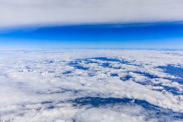 Obraz premium Aerial view above the clouds and misty mountain peaks covered with snow on a sunny day.China Tibet.