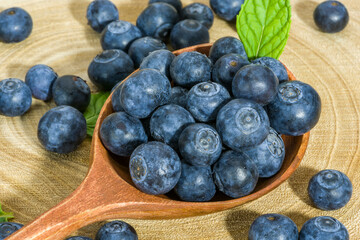 fresh blueberries in a wooden spoon over wooden table