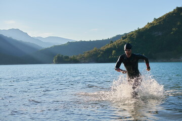 triathlon athlete starting swimming training on lake