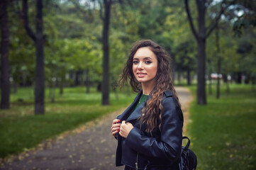 Fototapeta na wymiar Portrait of a young happy girl in a leather jacket on a walk in the autumn Park
