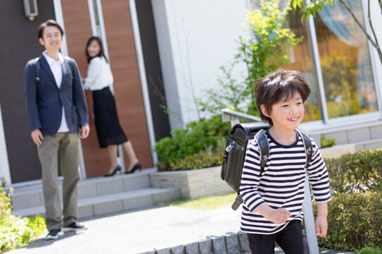 登校する小学生の男の子と見送る両親