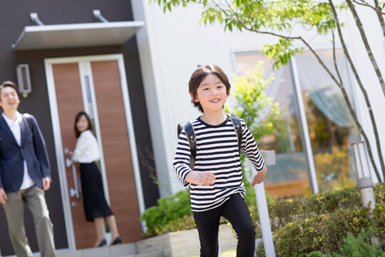 登校する小学生の男の子と見送る両親