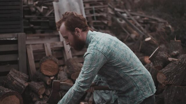 Young man in plaid shirt chopping wood on sawmill.
