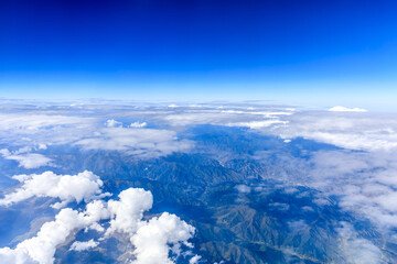 Fototapeta na wymiar Aerial view above the clouds and mountain peaks on a sunny day.mountain view from airplane.