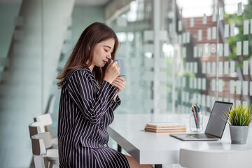 Asian beautiful business woman drinking coffee sitting at office.