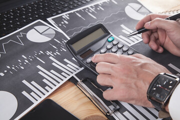 Businessman using calculator. Working in financial graphs