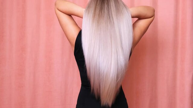 Slow motion shooting of a long blond hair of a young girl, backside view. Hair care concept.