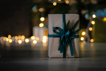 Brown gift box with black ribbon on dark background with garland.