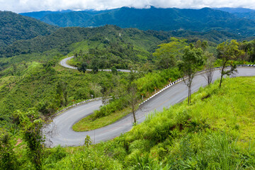 Fototapeta na wymiar Winding road, top view of the corner Look at the beautiful aerial view of asphalt roads, highways through mountains and forests in rainy season. For traveling and driving in nature. Nan thailand