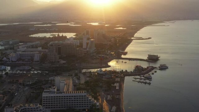 Sunrise over Eilat and The Red Sea, with waterfront hotels and Edom mountain ridge in the horizon, Aerial view.