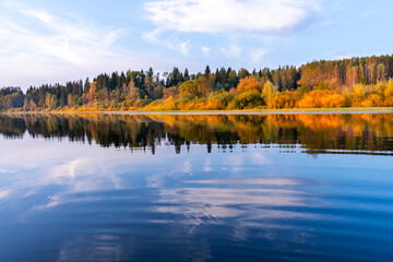 Banner overlooking a lake with bright blue water and a shore with an autumn forest reflected in the water