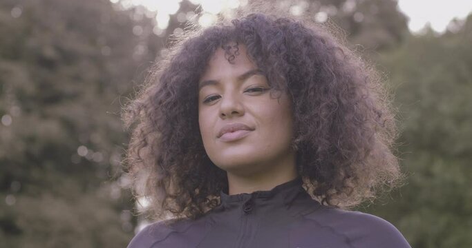 Portrait of Body positive young black female, Plus size obese overweight Afro American woman looking at camera in park