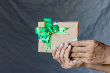 Hand holding gift box and bow tie canvas as a backdrop.