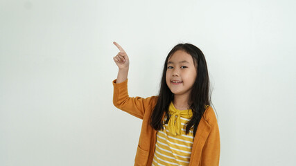 Adorable little girl pointing at wall. Isolated on white background