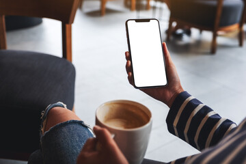 Mockup image of a woman holding mobile phone with blank screen while drinking coffee