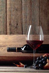 Red wine and a bunch of grapes on an old wooden table in the wine cellar.