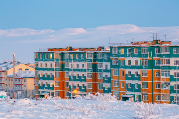 Winter landscape with a northern city in the Arctic. A view of the snow-covered tundra, colorful residential buildings and hills. Cold frosty February weather. Anadyr, Chukotka, Far North of Russia.