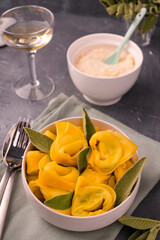 Tortelloni with sage leaves, ricotta and spinach. Italian pasta and white wine. Traditional Bologna cuisine, Emilia Romagna region. High quality photo. Copy space