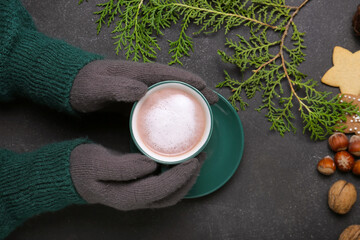 Hands with cup of tasty cocoa drink on dark background