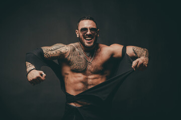 Angry guy. Fashion brutal guy with sexy body ripped shirt. Sexy man with muscular body and bare...