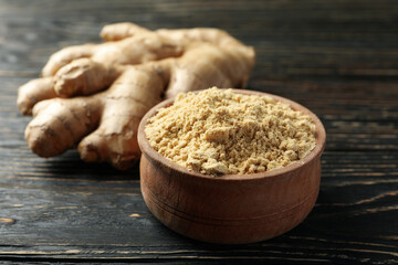 Ginger and bowl with ginger powder on wooden background